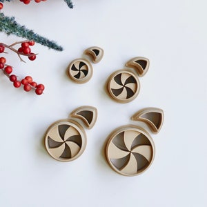 May include: Set of four brown plastic cookie cutters shaped like candy canes. The cutters are different sizes and have a swirl design.