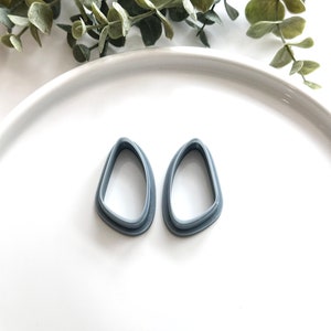 May include: Two gray plastic cookie cutters shaped like a teardrop.