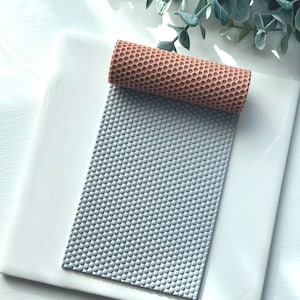 May include: A grey silicone sheet with a honeycomb pattern, and a brown silicone roller with a honeycomb pattern.