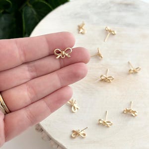 Op de afbeelding: Een paar gouden oorringen in de vorm van een strik. De oorringen zijn klein en delicaat en zouden een geweldig cadeau zijn voor een vriend of geliefde.