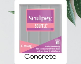 Pode incluir: Um pacote de argila para assar Sculpey Souffle Concrete. O pacote é rosa e branco e apresenta o logotipo da Sculpey, bem como as palavras "Souffle" e "Concrete". O pacote também inclui o peso da argila, 1,7 oz (48 g), e instruções para assar a argila.