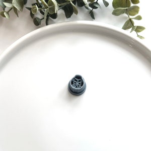 May include: A gray plastic shower head filter with a circular design. The filter has multiple small holes for water to flow through.