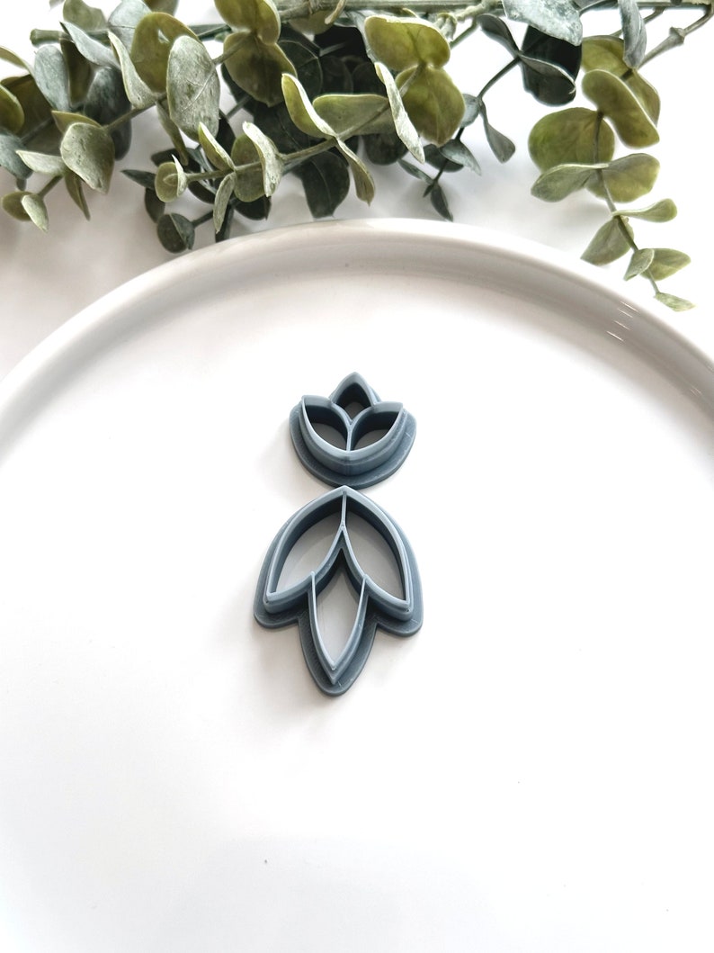 May include: A set of two gray plastic cookie cutters shaped like a flower with five petals.
