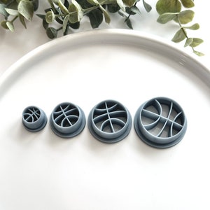 May include: Four gray plastic basketball-shaped cookie cutters of different sizes.