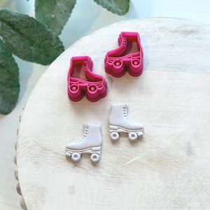 Puede incluir: Dos pares de dijes de patines, un par es rosa y el otro par es blanco.