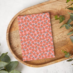 Puede incluir: Una tarjeta rosa con un patrón repetido de fruta naranja con hojas verdes.