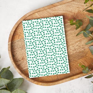 May include: A white card with a repeating pattern of green shamrocks.