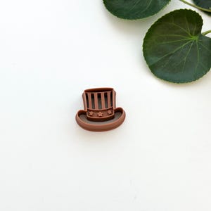 Könnte beinhalten: Ein brauner Plastik-Ausstecher in Form eines Zylinders mit Sternen und Streifen.