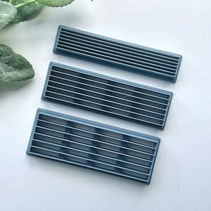 Peut inclure: Trois grilles d'aération en plastique gris de différentes tailles. Les grilles d'aération sont rectangulaires et faites d'un matériau nervuré.