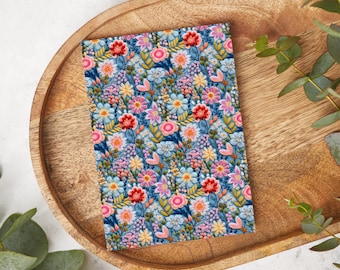 May include: A blue background with a floral pattern featuring pink, red, yellow, and white flowers. The flowers are surrounded by green leaves and stems.
