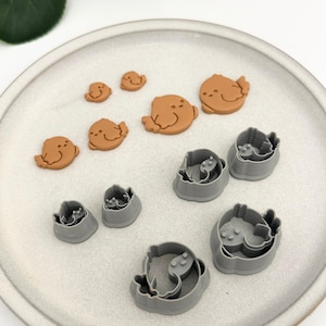 Könnte beinhalten: Ein Set mit 9 Ausstechern in Form eines Vogels. Die Ausstecher sind aus grauem Kunststoff und auf einem grauen Teller angeordnet. Auf dem Teller befinden sich auch 5 braune Ausstecher in Form eines Vogels.