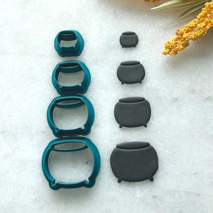 May include: Set of six teal cauldron cookie cutters and five black fondant cauldrons of varying sizes.