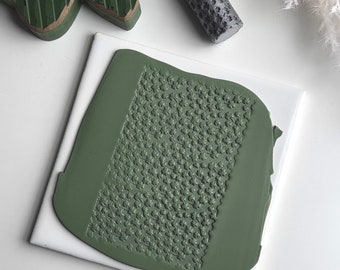 May include: A close-up of a green textured roller with a repeating pattern of small stars. The roller is on a white surface.