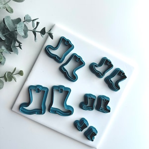 Könnte beinhalten: Ein Satz mit sieben blauen Plastik-Ausstechern in Form von Gummistiefeln. Die Ausstecher sind in verschiedenen Größen, der größte Ausstecher ist etwa 7,5 cm hoch.