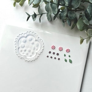 May include: A handmade wooden sign with the text "Welcome" in a playful font. The sign is painted white with a distressed finish, and features a small, decorative floral accent. It's designed for indoor or outdoor use.