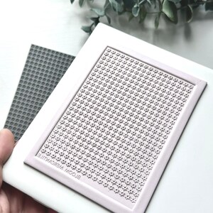 May include: A white silicone stamping block with a raised pattern of small flowers. The block is labeled "BLOOM MERCANTILE".