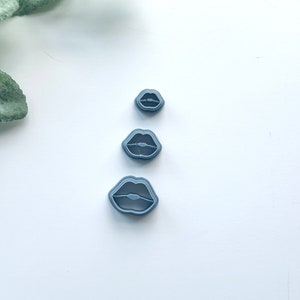 Peut inclure: Trois emporte-pièces en plastique gris en forme de lèvres, de différentes tailles.