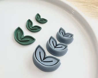 May include: A set of five leaf-shaped cookie cutters. Three are green and two are gray.