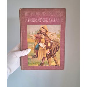 May include: A vintage book cover with a pink background and the title "The Pilgrim's Progress in Words of One Syllable". The cover features an illustration of four children walking along a path in a forest.