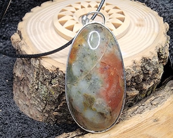 May include: A silver oval pendant with a colorful agate stone. The stone has shades of brown, red, white, and gray. The pendant is on a black cord.