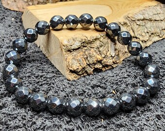 May include: A black hematite gemstone bracelet with faceted beads. The bracelet is made of natural stones and is approximately 8 inches in length.