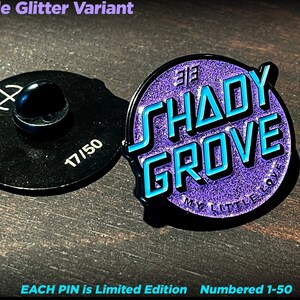 Könnte beinhalten: Lilafarbener Glitzer-Emaille-Pin mit dem Text "Shady Grove" in blau umrandeten Buchstaben. Der Pin ist mit 17/50 nummeriert und hat einen Durchmesser von etwa 3,18 cm.