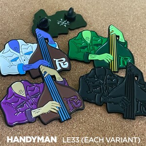 Könnte beinhalten: Vier Emaille-Pins mit einer Cartoon-Figur, die Bass spielt. Die Pins sind in verschiedenen Farben: weiß, grün, lila und schwarz. Die Pins sind mit "HANDYMAN LE33 (JEDE VARIANTE)" beschriftet.