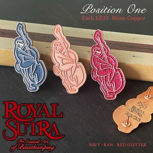 Könnte beinhalten: Drei Emaille-Pins mit einer Cartoon-Illustration einer Person, die Bass spielt. Die Pins sind in drei verschiedenen Ausführungen: marineblau, rohes Kupfer und roter Glitzer. Die Pins sind mit "Position One" und "Each LE33 Shiny Copper" beschriftet. Die Pins sind auch mit "ROYAL SUTRA" und "The Sensual Art of Bassthumping" beschriftet.