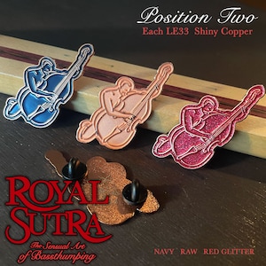 Könnte beinhalten: Drei glänzende Bass-Spieler-Pins aus Kupfer. Die Pins sind in den Farben Marineblau, Rohkupfer und rotem Glitzer. Die Pins befinden sich auf einer Holzoberfläche. Der Text "ROYAL SUTRA The Sensual Art of Bassthumping" ist in der linken unteren Ecke des Bildes sichtbar. Der Text "Position Two Each LE33 Shiny Copper" ist in der rechten oberen Ecke des Bildes sichtbar. Der Text "NAVY RAW RED GLITTER" ist in der rechten unteren Ecke des Bildes sichtbar.