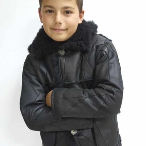 Könnte beinhalten: Eine schwarze Schaffelljacke mit einem Pelzkragen und einem gesteppten Design. Die Jacke hat einen Knopfverschluss und wird von einem jungen Menschen getragen.