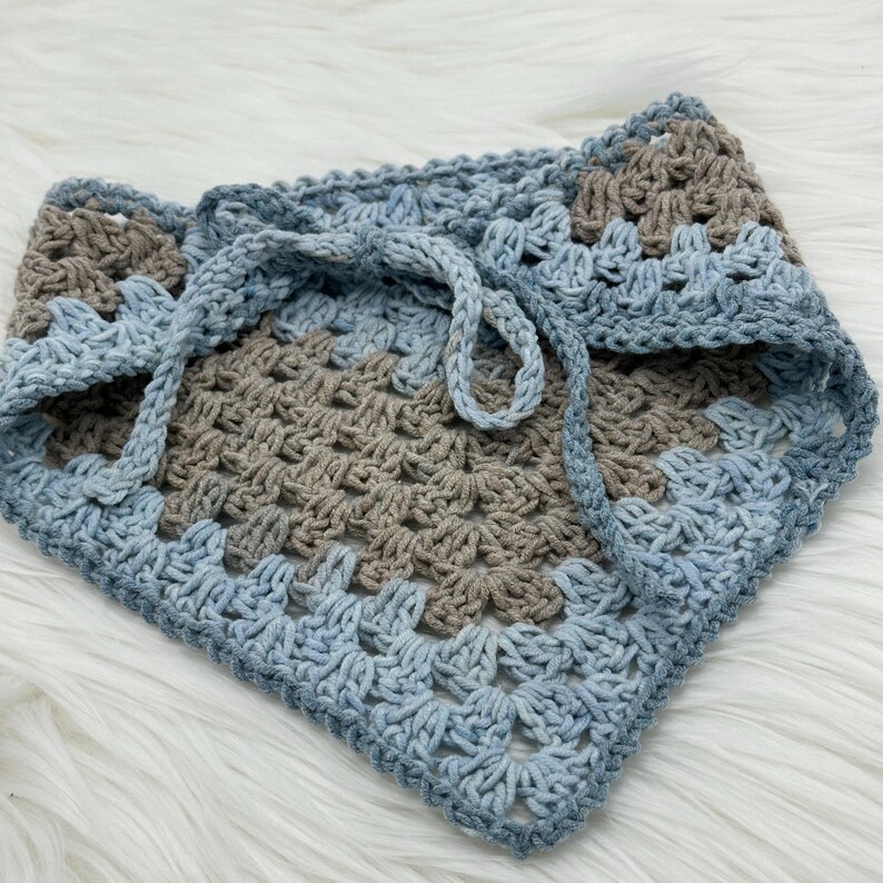 May include: A crocheted scarf in shades of blue and brown with a tie closure.
