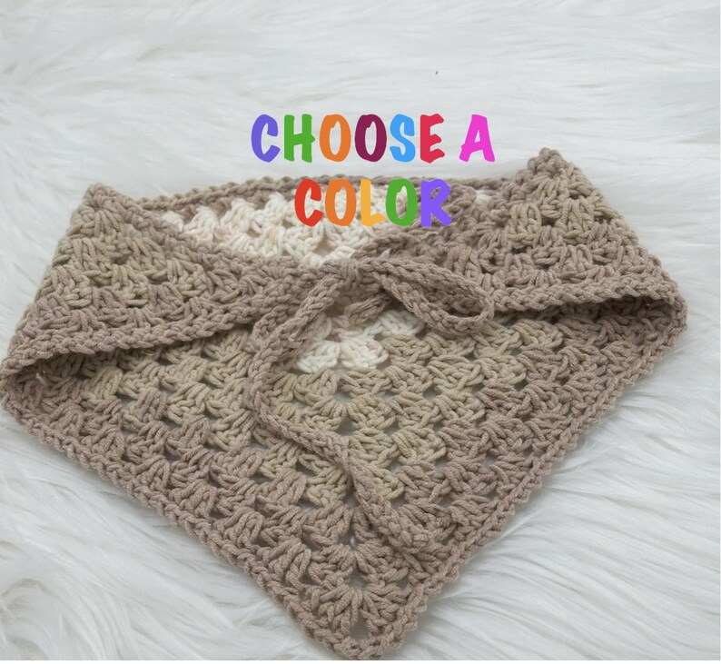 May include: A crocheted triangle scarf in a beige and white color gradient. The text "CHOOSE A COLOR" is written in rainbow letters above the scarf.