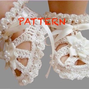 Op de afbeelding: Een paar witte gehaakte babyschoentjes met parelversiering en satijnen lintjes. De schoentjes hebben een delicaat kantpatroon en zijn perfect voor een speciale gelegenheid.