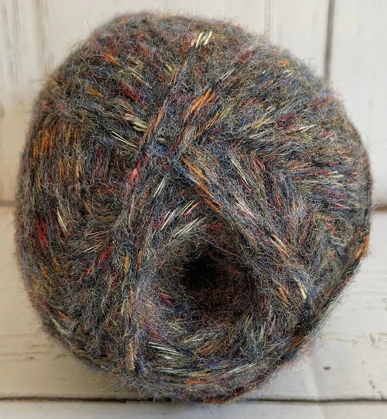 May include: A ball of yarn with a mix of grey, brown, orange, and red colors. The yarn has a fuzzy texture.