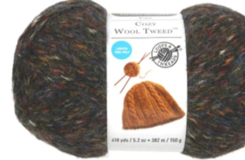 May include: A skein of Loops & Threads Cozy Wool Tweed yarn in a brown, black, and blue colorway. The yarn is a blend of wool and acrylic and is 418 yards / 5.2 ounces. The label also shows a knitted hat in a brown color.