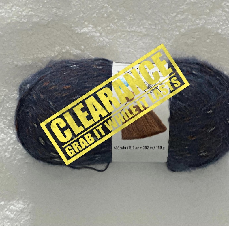 May include: A skein of blue yarn with brown and orange flecks. The yarn is labeled "CLEARANCE GRAB IT WHILE IT LASTS" and has the following information: 418 yds / 5.2 oz - 382 m / 150 g.