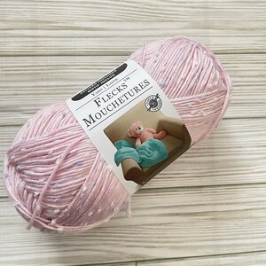 Könnte beinhalten: Ein rosa Garnknäuel mit weißen Punkten. Das Etikett lautet "Flecks Mouchetures Yarn | Laine TM".