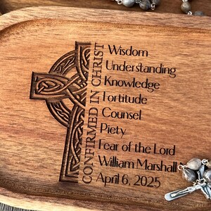 Peut inclure: Un plateau en bois avec un motif de croix celtique grav&eacute; avec le texte "Confirm&eacute; en Christ" et une liste de vertus&nbsp;: Sagesse, Compr&eacute;hension, Connaissance, Force, Conseil, Pi&eacute;t&eacute;, Crainte du Seigneur. Le plateau comprend &eacute;galement le nom "William Marshall" et la date "6 avril 2025".
