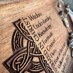 Peut inclure: Un plateau en bois avec un motif de n&oelig;ud celtique et les mots "Sagesse, Compr&eacute;hension, Connaissance, Force, Conseil, Pi&eacute;t&eacute;, Crainte du Seigneur" grav&eacute;s dessus. Le plateau est &eacute;galement dot&eacute; d'un chapelet avec un charme en argent.