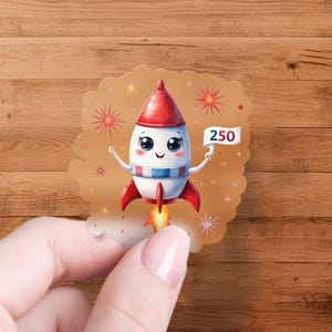 Peut inclure: Un autocollant fantaisiste représentant une fusée de dessin animé avec un cône de nez et des ailerons rouges, une section médiane à rayures bleues et blanches et un visage souriant. La fusée porte une bannière avec le numéro 250.