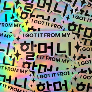 May include: A close-up of iridescent holographic stickers with the text "I got it from my" and the Korean word "머니" (money) in black text. The stickers are arranged in a random pattern and have a glittery finish.
