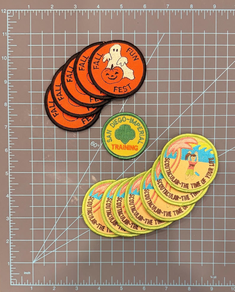 May include: A collection of embroidered patches. Several orange patches with "FALL FUN FEST" text and a ghost and pumpkin design. Other patches include "SAN DIEGO-IMPERIAL TRAINING" and "SCOUTACULAR - THE TIME OF YOUR LIFE" designs.