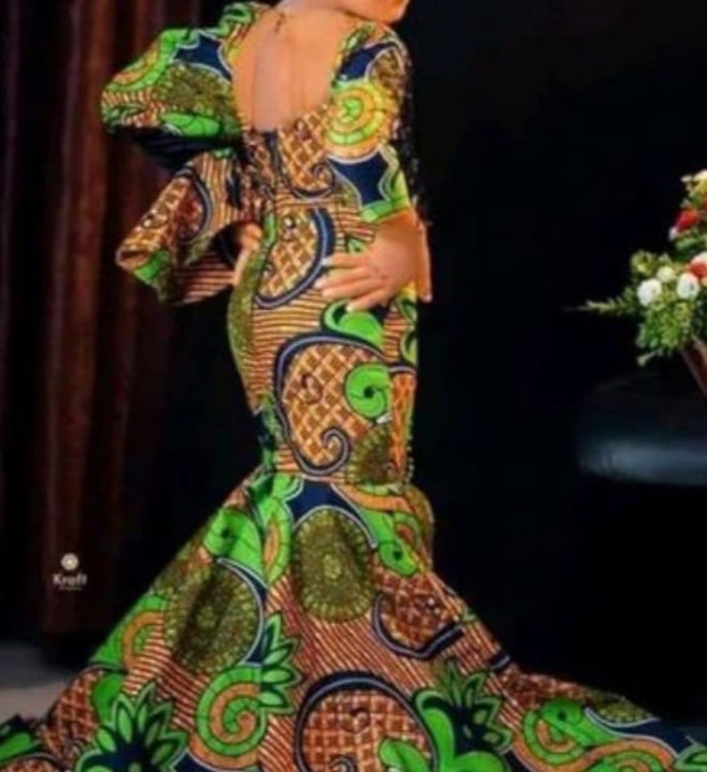 May include: A young girl wearing a long, green, orange, and blue patterned dress with a mermaid-style skirt.