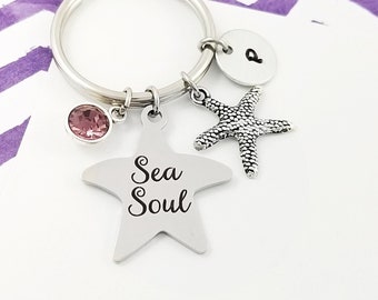 May include: Silver keychain with a star charm that says "Sea Soul", a pink crystal charm, a starfish charm, and a silver charm with the letter "Q".