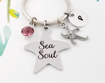 May include: A silver keychain with a star charm that says "Sea Soul" and a small pink crystal charm. The keychain also has a silver starfish charm and a silver disc charm with the letter "P" on it.