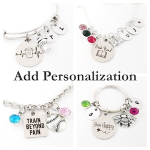 May include: Four different charm bracelets with various charms, including a coffee cup, a book, a baseball, and a bee. The bracelets are made of silver metal and have different colored crystals.