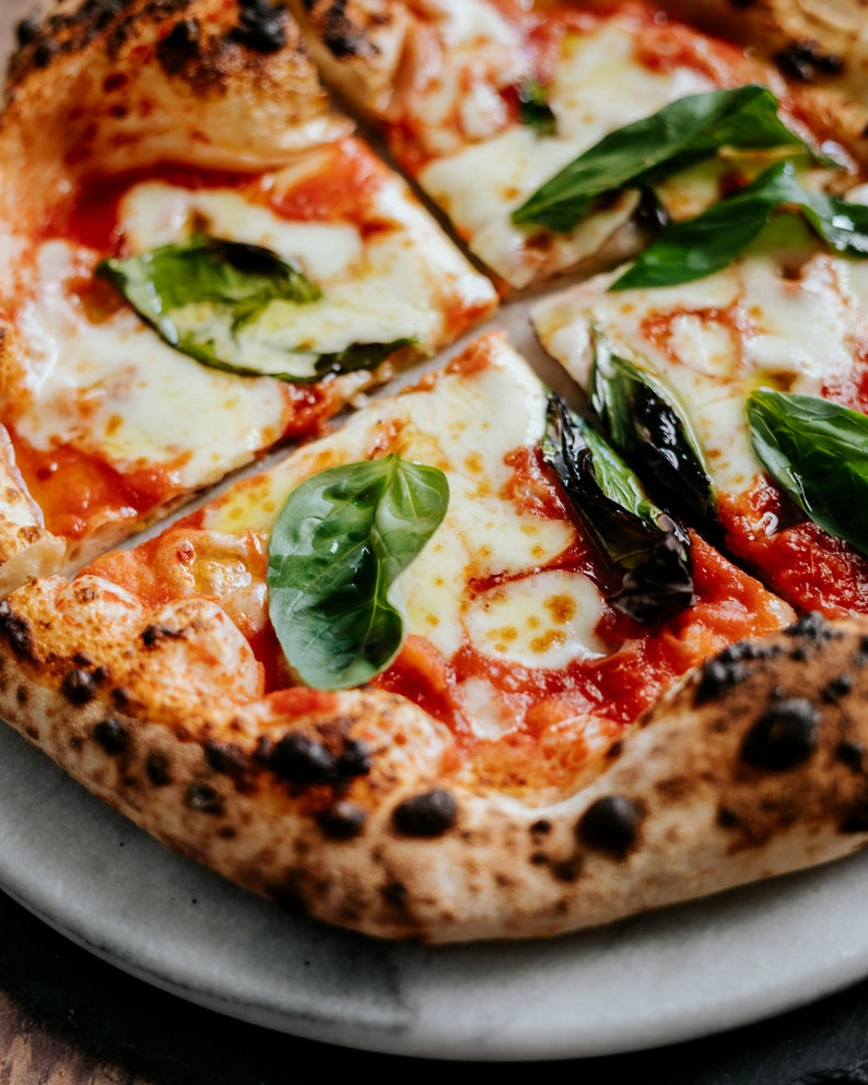 May include: A close-up of a pizza with a crispy crust, red sauce, melted mozzarella cheese, and fresh basil leaves.
