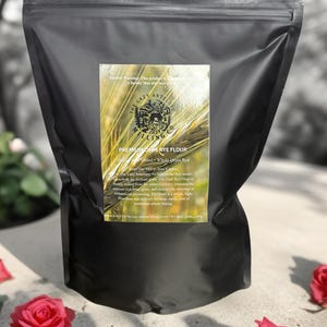 May include: A black bag of Premium Dark Rye Flour from The Lazy Antelope Milling Co. The label includes text about the flour's milling process and its high fiber content. Red roses are scattered at the bottom of the image.