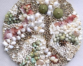 May include: A circular mosaic made of various seashells in shades of white, brown, pink, and green. The shells are arranged in a swirling pattern, creating a visually appealing and textured artwork.