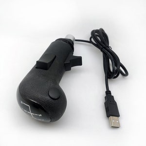 K&ouml;nnte beinhalten: Ein schwarzer, USB-angeschlossener manueller Schalthebel mit einem 5-Gang-Schaltmuster und einem Knopf an der Seite.
